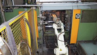 Bild 1: Der Roboter entnimmt in einem Arbeitsschritt das Teil aus der Maschine und besprüht die Form.  (Bild: Kawasaki)