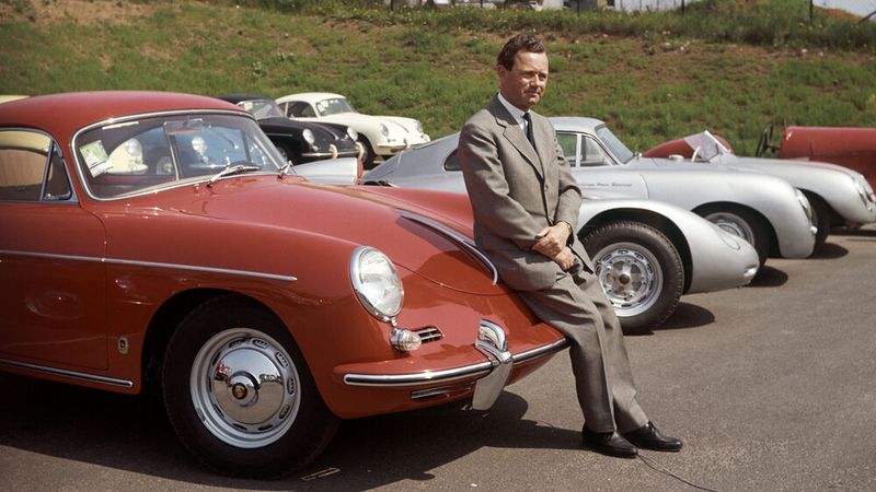 Porsche-Gründersohn Ferry Porsche auf einem 356 B im Werk II in Stuttgart. Er war maßgeblich an der Entstehung des Wagens beteiligt. Beim „B“ sind die Scheinwerfer und die Stoßstangen höher gesetzt, sodass der Wagen freundlicher erschien. Das Lenkrad erhielt eine versenkte Nabe, Drehfenster verbesserten die Frischluftzufuhr und die Heckscheibe wurde von einer Heizdüse beschlagfrei gehalten. (Bild: Porsche)