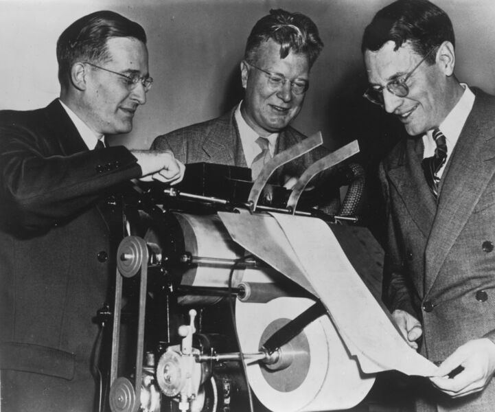 Chester Carlson (M.) mit Kollegen vor einer der ersten kommerziellen Kopiermaschinen (Xerox)
