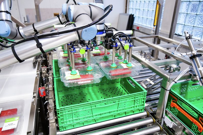 Am End-of-Arm von zwei Cobots nehmen PXT-Greifer im Zusammenspiel mit der Compact-Pump GCPi folierte Fleischpackungen prozesssicher und energieeffizient auf. (Bild: J. Schmalz GmbH)