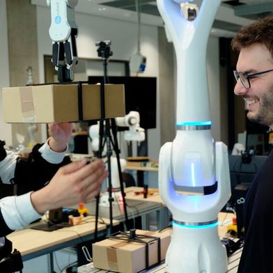 Federico Masiero (li. mit Exoskelett) und Emanuele Aimi testen die Zusammenarbeit mit einem Roboter von Neura Robotics.  (Bild: Andreas Schmitz / TUM)