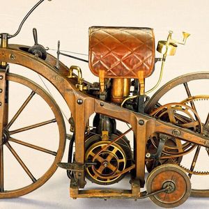 Daimlers und Maybachs nächster Schritt nach Erfindung der Standuhr war deren Einbau in ein Fahrzeug. Aus Kostengründen entschieden sie sich für ein hölzernes, mit Stützrädern versehenes Zweirad. Den Rahmen bauten sie aus Hickory-Holz, das mit Eisenplatten verstärkt wurde. Der Motor wurde vertikal zwischen die Holzstützen und Kreuzstreben eingebaut. Über den an einer Scheibe lösbaren Antriebsriemen konnte die Kraft unterbrochen werden. Der Auspuff befand sich unmittelbar unter dem wie ein Reitsattel geformten Ledersitz. Über Schnüre am Lenker konnte die auf das Hinterrad wirksame Klotzbremse betätigt werden.(Bild:  Mercedes-Benz)