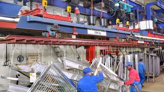 An Ringbahnen durchlaufen die feuerzuverzinkenden Teile die Bäder. Ausgangspunkt und Endpunkt sind die Aufgabe-/Abnahmestationen, an denen die Traversen abgesenkt werden. (Bild: Demag)