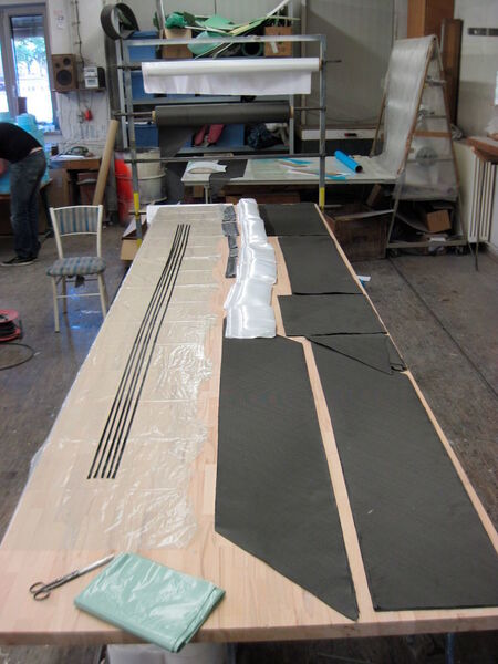 Natürlich mussten auch etliche Lagen an Kohle- und Glasfasergewebe ausgemessen und zugeschnitten werden. Bei größeren Laminieraktionen ist es sehr wichtig alles gut vorzubereiten, da durch die beschränkte Verarbeitungszeit des Harzes es sonst schnell sehr stressig werden kann. (Akaflieg Karlsruhe)