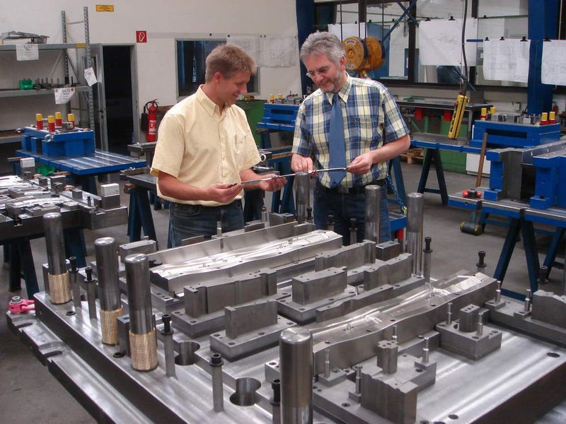 Eberhard Budde (re) und Burkhard Gerling von der Gütersloher Werkzeugbau GmbH begutachten die ersten Abpressungen des Bauteils vor dem Oberteil des Formstanzwerkzeugs. (Archiv: Vogel Business Media)