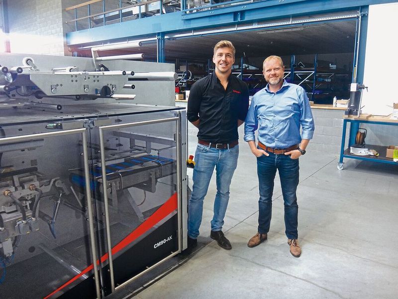 Filip Lamiroy (TG Packaging) und Sven Verlinden (SigmaControl) an der neu entwickelten CM90-X-Faltmaschine. (Sigmatek)