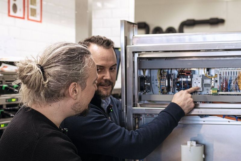 Bild 10: Roland Ambrosch und Oliver Reiter am Schaltschrank beim Blick auf einen LDH-Sensor. (Bild: ifm)