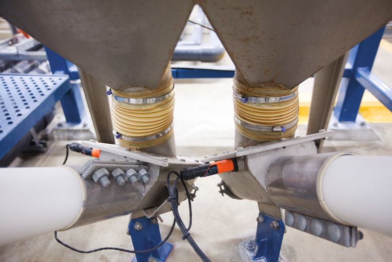 Fig. 6: Fluoride powder flows from double outlet hopper through sealed connections to the two flexible screw conveyors that move it to the two storage hoppers. (Picture: Flexicon (Europe) Ltd.)