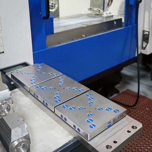 In the foreground is the trunnion equipped with Lang workholding plates that is usually rotated by the 4th-axis indexing head on the Brother Speedio’s table.(Source:  Whitehouse Machine Tools)