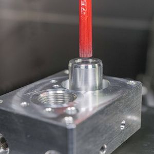 Rechter Ausbruch am Bohrungsgrund: die Tieflochbohrung endet halboffen in der Bodenfläche und im Freistich entsteht ein Grat, der nur durch den Einsatz der Keramikfaser Cross-Hole Bürste Typ Bücha127M entgratet werden kann. Unter Drehzahl spreizen sich bei diesem Bürsten-Typ die einzelnen Fasern durch die Fliehkraft auf und entfernen somit sanft entstehende Mikro-Grate. (Bild:  Kempf)