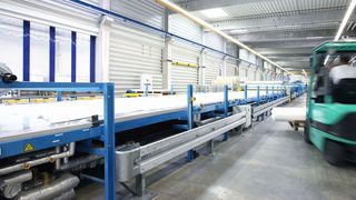 Auf mehren 100 m langen Produktionslinien werden CFK-Bahnen mit Oberflächenversiegelung für Fahrzeugaufbauten hergestellt.  (Bild: Lamilux)