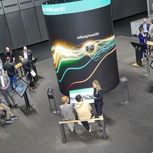 Blick in die Arburgsolutionworld, wo man an sechs Stationen rund um die hier zu sehende, plakative LED-Säule individuell beraten wurde. Und zwar zu Themen, wie Effizienz, Automatisierung, Digitalisierung und Fachkräftemangel im Rahmen der Kunststoffverarbeitung.(Bild:  Arburg)