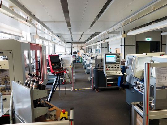 Blick in die Ausbildung in der 4. Etage: Im Vordergrund das Podest auf dem links die Kunzmann Universal-Fräs- und Bohrmaschine WF 610 MC und rechts die zyklengesteuerte Präzisions-Drehmaschine Weiler E30 stehen. Links und rechts vom Gang sind die Praktikant GSD und die Praktikant VCplus zu sehen. Blick in die Ausbildung in der 4. Etage: Im Vordergrund das Podest auf dem links die Kunzmann Universal-Fräs- und Bohrmaschine WF 610 MC und rechts die zyklengesteuerte Präzisions-Drehmaschine Weiler E30 stehen. Links und rechts vom Gang sind die Praktikant GSD und die Praktikant VCplus zu sehen.
