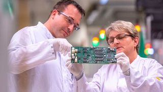 Continental-Mitarbeiter überprüfen eine Platine für ein Fahrzeug-Steuergerät in der Elektronikfertigung im Werk von Continental. Das Unternehmen will radikal umbauen und den Schwerpunkt auf Sensorik, Elektronik und Software ausrichten. (Bild: Armin Weigel/dpa)