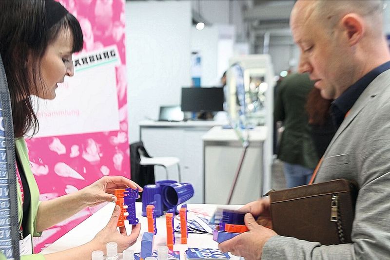 Das orange-blaue Kunststoffteil ist der Polyman: eine Zwei-Komponenten-Anwendung, die je zur Hälfte einer kunststoffgerechten und einer nicht kunststoffgerechten Bauteilkonstruktion entstammt. Alles Gute und alles Schlechte in einem Teil vereint und auf einen Blick erkennbar. (Bild: Maschinenmarkt)