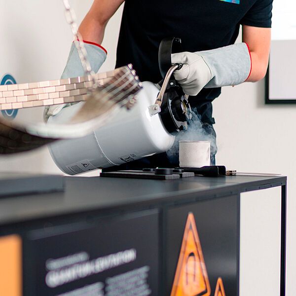Quantenlevitation Teil 1: Flüssiger Stickstoff wird in einen Behälter mit einer Metallscheibe gegossen. Links im Bild die „Achterbahn“ aus magnetisierten Metallstücken.