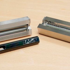 Markant und unverwechselbar: Das Lamy-Logo auf dem Behälter eines Füllfederhalters sowie die gefrästen, noch unbeschichteten Formeinsätze.(Bild:  Röders)