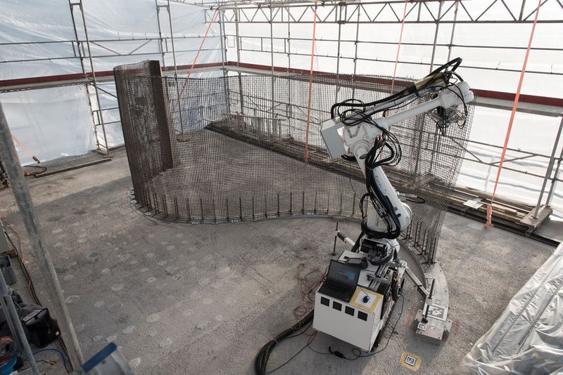 Der Bauroboter „In situ Fabricator“ baut mithilfe der „Mesh Mould“-Technologie ein Stahldrahtgitter im Forschungsgebäude. Die Technologie kombiniert die beiden Funktionen Schalung und Bewehrung des Betons in einem Stahldrahtgitter. Die Fertigung einer Wand geschieht in einem einzigen von Robotern kontrollierten Prozess. (Bild: NCCR Digital Fabrication, 2017)
