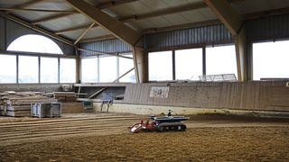 Der autonome Reiterhofassistent glättet aktuell im Dauertestbetrieb den Boden einer Reithalle. 
 (Bild: Fraunhofer IPA)