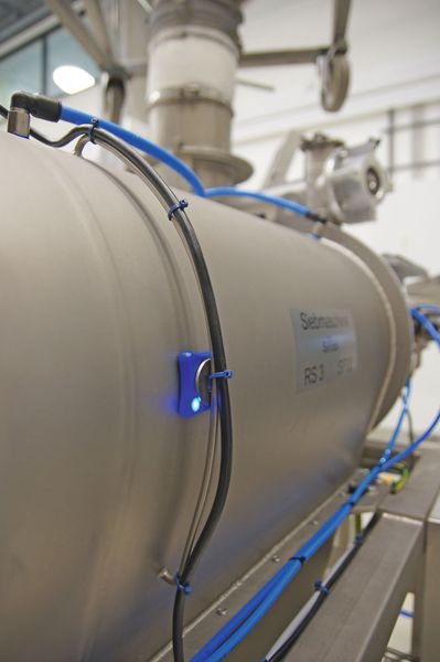 Ein Sensor (blau leuchtend), der an der Fertigungsanlage angebracht wurde, übermittelt die Daten, die von den Start-ups auf dem Hackathon aufgegriffen und in konkrete Projektideen umgesetzt wurden. (Bild: Oliver Thiel/Zeppelin)