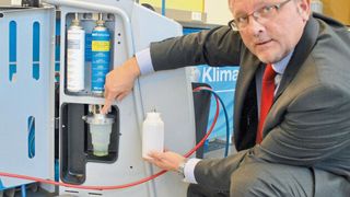 „Low Emisson“ heißt die Waeco-Klimaservice-Technologie, mit der Werkstätten der Umwelt, aber auch ihrem Geldbeutel etwas Gutes tun können. Guido Sasse, Head of Business Development and Marketing bei Waeco, zeigt den dabei zum Einsatz kommenden Altölbehälter, der sich erkennbar von bekannten Modellen unterscheidet. Darüber: die ebenfalls neuartigen Behälter für Frischöl und Kontrastmittel. (Bild: Dominsky)