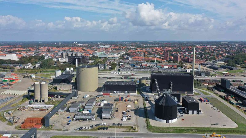 Warmwasserspeichertank, Wärmepumpenhalle und Holzschnitzelanlage (von links) im Hafen von Esbjerg, Dänemark.(Bild:  DIN Forsyning)