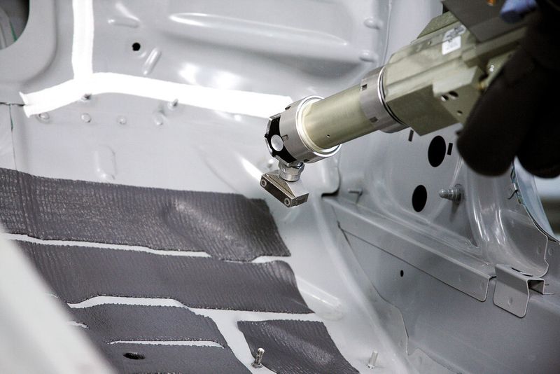 Die automatisierte Applikation von Dämmmaterial im Fussraum eines Automobils ersetzt eine klassische Handapplikation: das Einlegen von Dämmmatten. Die «spritzbare Akustikmasse» (SAM) wird im sogenannten Flatstream-Verfahren aufgebracht. (Bild: SCA Schucker)