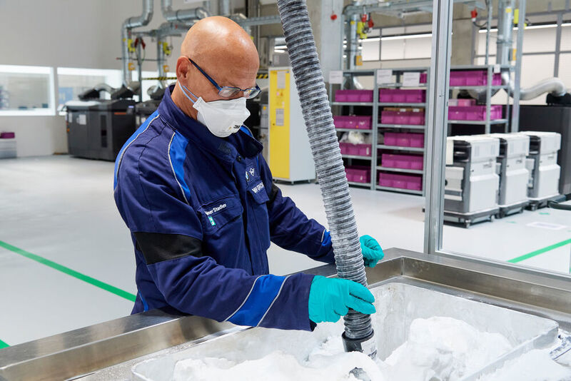 Bauteile entpulvern: Ein Mitarbeiter saugt überschüssiges Pulver ab, anschließend werden die Bauteile mit einem Glasperlenstrahl endbearbeitet. (Tom Kirkpatrick/BMW)