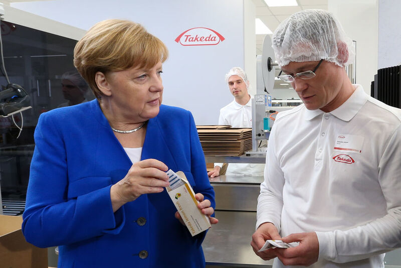Bundeskanzlerin Angela Merkel nimmt die ersten Packungen der neuen Anlagen entgegen. Eigens für den Eröffnungstag produzierte Takeda Zitronenbonbons. (Takeda)