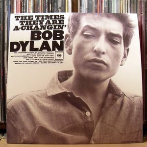 Robert Allan Zimmerman sagt den wenigsten etwas, Mr. Tambourine Man schon. Unter diesem Namen kam Bob Dylan am 24.5.1941 Duluth, Minnesota zur Welt. Schon in der Schule spielte er in verschiedenen Bands. Im Herbst 1959 kehrte Dylan nach eigenen Angaben der „Wildnis“ den Rücken und schrieb sich für einen Kunststudiengang mit Hauptfach Musik an der University of Minnesota in St. Paul ein. Dort nahm er an keinem einzigen Kurs teil, lernte aber mit der Folkmusik von Pete Seeger, The Kingston Trio und Woody Guthrie kennen. Etwas über ein Jahr später hatte der Junge aus der Provinz seine Berufung gefunden. Er wollte Musiker werden. Bei seinen Eltern stieß er zunächst nicht gerade auf Begeisterung. Der Sohn sollte in die Firma seines Vaters einsteigen, der als selbstständiger Elektriker arbeitete. Ein Jahr gaben die Eltern ihrem Sprößling Zeit. Sollte die Karriere nicht anlaufen, müsse er etwas „Richtiges“ lernen. Doch der Erfolg stellte sich ein. Dylan stand eine Karriere als einer der einflussreichsten Künstler des 20. Jahrhunderts bevor.