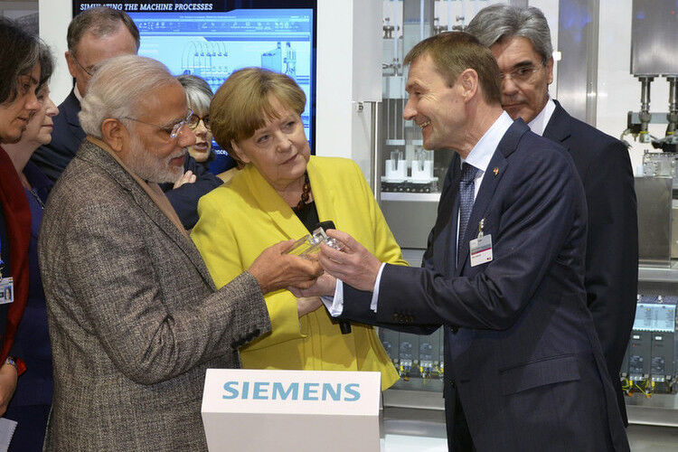 Bei ihrem Rundgang informiert sich die Bundeskanzlerin Angela Merkel und Indiens Premierminister Modi (links) über das Produzieren in Losgröße eins. Am Siemens-Stand produzieren sie sich ein personalisiertes Parfum-Flacon. Die Siemens-Vorstände Joe Kaeser (verdeckt) und Klaus Helmrich. (Foto: Frank Jablonski)