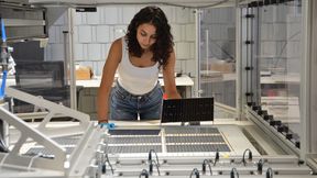 The project manager at Fraunhofer ISE, Najwa Abdel Latif, inspects the interconnected solar cells on the shingle matrix stringer at Fraunhofer ISE. (Source: Fraunhofer ISE / Sophia Bächle)