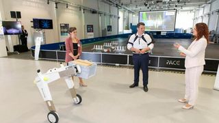 Bundesarbeitsminister Heil am Fraunhofer-Institut für Materialfluss und Logistik IML mit körperentlastendem Exoskelett, das man dort testet. Im Vordergrund der AMR „evoBOT“. (Bild: Fraunhofer IML)