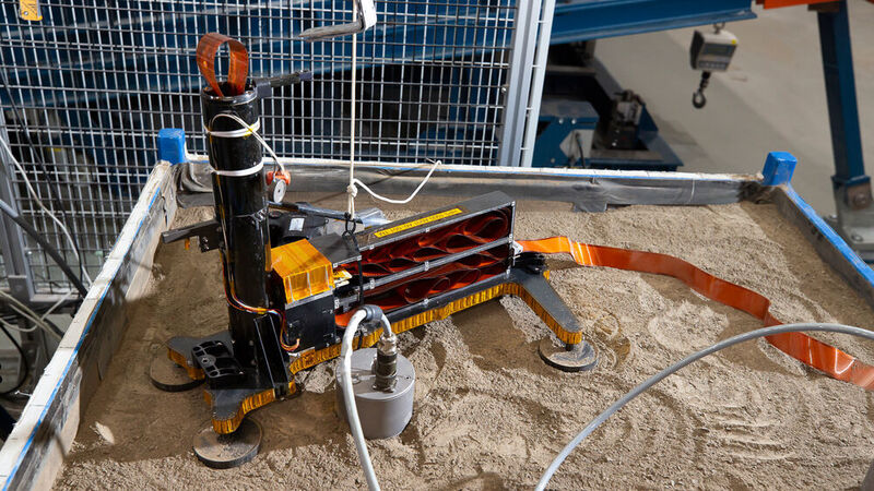 Das Ersatzmodell des Maulwurfs wird im DLR-Institut für Raumfahrtsysteme in Bremen in einer Box aus Sand getestet. Bei allen Versuchen lauscht ein Seismometer auf die Tätigkeiten des irdischen Mauswurfs, das vor dem HP3-Experiment auf dem Sand zu sehen ist. (HP3-Ersatzmodell im DLR-Testlabor in Bremen / CC BY 3.0)