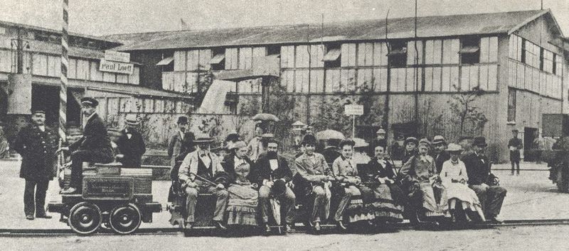 140 Jahre elektrische Lokomotive  „Unsere electrische Eisenbahn[…] macht jetzt hier viel Spectakel. Sie geht in der That über Erwartung gut. Es werden in einigen Stunden täglich gegen 1000 Personen à 20 Pfennig für wohlthätige Zwecke befördert. […] Es lässt sich darauf in der That jetzt was bauen!“ So schrieb Werner von Siemens am 12. Juni 1879 an seinen Bruder Carl. Diese von Siemens & Halske gebaute erste brauchbare „electrische Eisenbahn“ der Welt bestand aus einer kleinen elektrischen Lokomotive und drei Personenwagen für jeweils 6 Fahrgäste. 1879 drehte sie auf einer 300 Meter langen Kreisbahn auf der Berliner Gewerbeausstellung erstmals ihre Runden. Angetrieben wurde die kleine Lokomotive von einem 2-poligen Gleichstrom-Reihenschlussmotor mit einer Leistung von 2,2 kW bei 150 V und erreichte mit Wagen eine Geschwindigkeit von 6 bis 7 km/h. Innerhalb von vier Monaten wurden so über 86.000 Fahrgäste befördert. 140 Jahre später ist der elektrische Antrieb aus dem täglichen Bahnbetrieb nicht mehr wegzudenken. (Bild:  © Juulijs-stock.adobe.com)