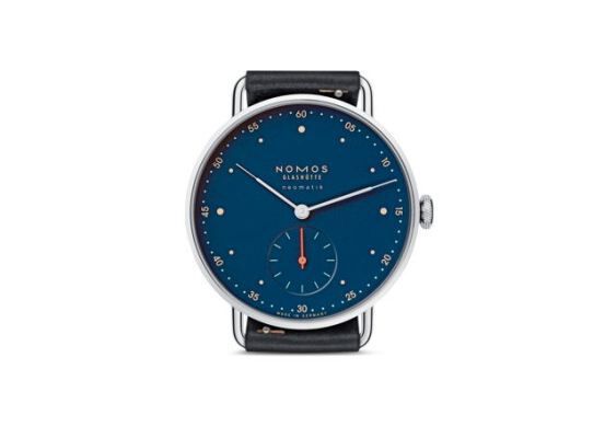 Armbanduhr Metro neomatik nachtblau: Die flach gebaute Armbanduhr Metro neomatik nachtblau besitzt eine gleichermaßen klare wie auch markante Minuterie sowie schlanke Zeiger. Ihr Zifferblatt ist, wie bereits der Name andeutet, mitternachtsblau. Im Zusammenspiel mit subtilen Details in Grün und Orange erzeugt die Gestaltung einen großstädtischen, kosmopolitischen Charakter. Das herstellereigene Manufakturkaliber mit Automatikaufzug, DUW 3001, verbindet Hightech-Fertigungstechniken mit sorgfältiger Handarbeit, Veredelung und Montage. Für Präzision sorgt das NOMOS-Swing-System mit temperaturgebläuter Unruhspirale, Hersteller NOMOS Glashütte/SA, Deutschland.  (Bild: Red Dot / )