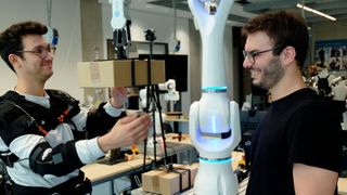 Federico Masiero (li. mit Exoskelett) und Emanuele Aimi testen die Zusammenarbeit mit einem Roboter von Neura Robotics.  (Bild: Andreas Schmitz / TUM)