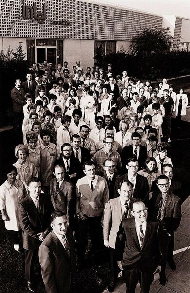 Die ersten 106 Angestellten von Intel im Jahr 1969. Links und rechts vorn die beiden Gründer Robert Noyce und Gordon Moore. Ganz rechts in der zweiten Reihe Andy Grove. Das Bild wurde noch vor dem ersten Intel-Firmengebäude in Mountainview, Kalifornien aufgenommen. (Intel)