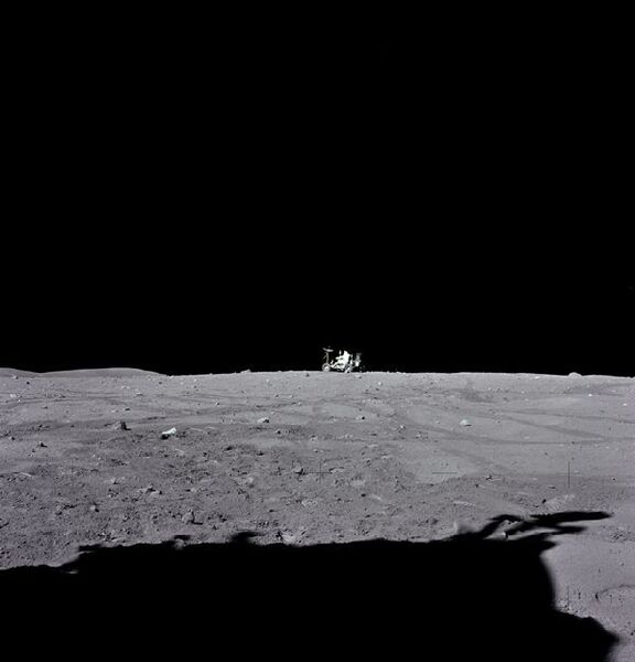 Apollo-16-Astronaut John W. Young beim „Parken“ des Rovers nach dem dritten Mondausflug der Mission. (EVA-3). Auf dem von Kommandant Charles M. Duke Jr.in Richtung Süden aufgenommene Foto zeigt die Flanken des Stone Mountains links am Horizont. Sichtbar ist auch der Schatten der Landefähre im Vordergrund. (Bild: NASA)