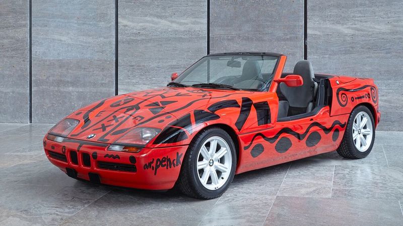 Das BMW-Modell, das der gebürtige Dresdner A. R. Penck – bürgerlich Ralf Winkler – nach seinen Vorstellungen gestaltete, ist an für sich schon ein Kunstwerk, eine Rarität: der BMW Z1. Mit seiner für die damaligen Zeit radikal neuen Formensprache und den versenkbaren Seitentüren ist der BMW Z1 bis heute ein Meilenstein der BMW Automobilgeschichte. Penck schuf seinen Beitrag zur Reihe der BMW-Art-Cars vier Jahre nach der Premiere des Roadsters. Inspiriert von Höhlenmalereien, kreierte er abstrakte Figuren und Zeichen. Was sie bedeuten? Versuchen Sie sich an einer Interpretation … Der Künstler selbst hat nie zu einer Dechiffrierung beigetragen – was sicher auch Teil des Reizes ist, den der Kunst-Sportwagen ausstrahlt. (Bild: BMW)