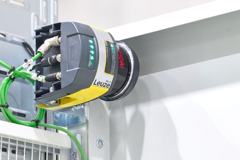 Sicherheits-Laserscanner RSL 400 von Leuze sichern den Zugang an den Materialübergabestationen zuverlässig ab. Sie erzeugen ein vertikales Schutzfeld und geben nach erfolgreicher Anmeldung des mobilen Roboters einen Bereich frei. Durch diesen liefert der mobile Roboter die Ware an. Seitlich neben dem Fahrzeug bleibt der Zugang weiterhin gesichert. (Bild: Leuze)