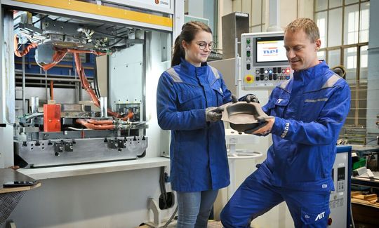 Angelika Cerny und Georg Kuscher vom AIT mit einem bei nur rund 500 °C einwandfrei umgeformtem Titanbauteil. Das Beste: Statt Umformwerkzeuge aus Nickelbasislegierung kann man nun einfach Warmarbetsstähle hernehmen.(Bild:  AIT / Joh. Zinner)