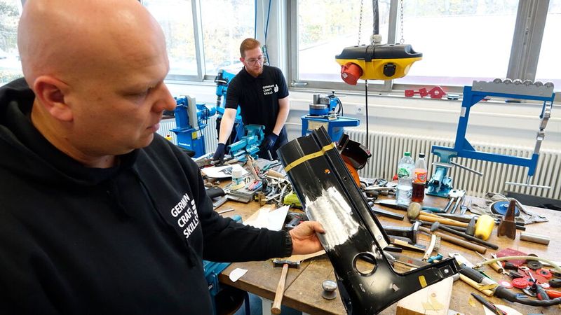 Steffen Fuchs, Referatsleiter Berufsbildung beim Zentralverband Karosserie- und Fahrzeugtechnik e.V., zeigt, was die Craft-Skill-Teilnehmer im Fall Karosserieinstandhaltungstechnik anfertigen bzw. bearbeiten durften. (Bild: Dominsky – VCG)