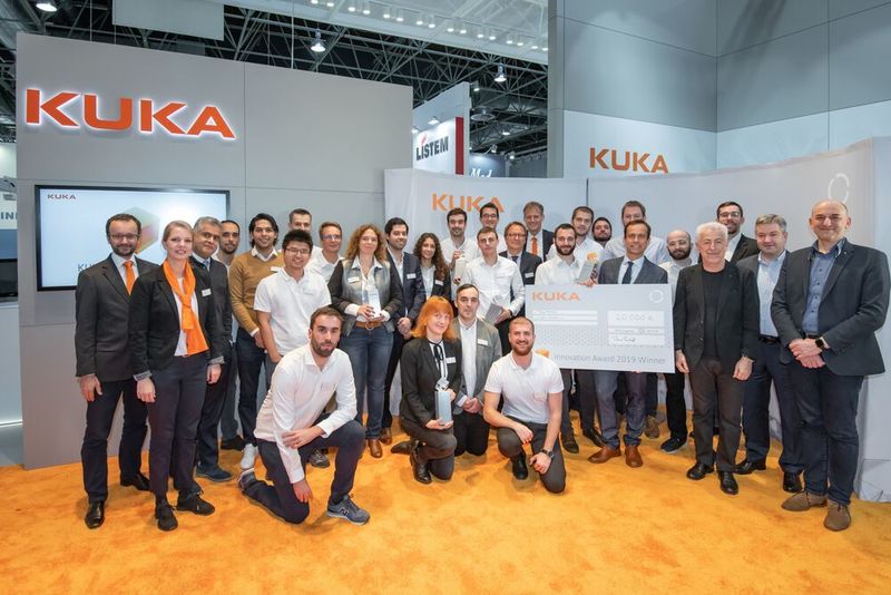 Große Bühne auf der Medica für alle Finalisten und Juroren des Kuka Innovation Award 2019. In der Mitte das siegreiche Team Roboforce, das für die Entwicklung einer robotergestützten Lösung zur magnetischen Endoskopie ausgezeichnet wurde. (Kuka)