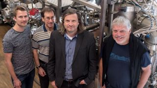 Das Forscherteam Tobias Löffler, Alan Savan, Alfred Ludwig und Wolfgang Schuhmann (von links) vor der kombinatorischen Sputteranlage, in der die Nanopartikelbibliotheken hergestellt wurden. (RUB, Kramer  )