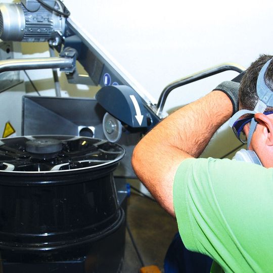 Mit dem geführten Rotationsschleifer bearbeitet der Fachmann die Felge auf dem Drehtisch. (Foto:  Holz/»kfz-betrieb«)