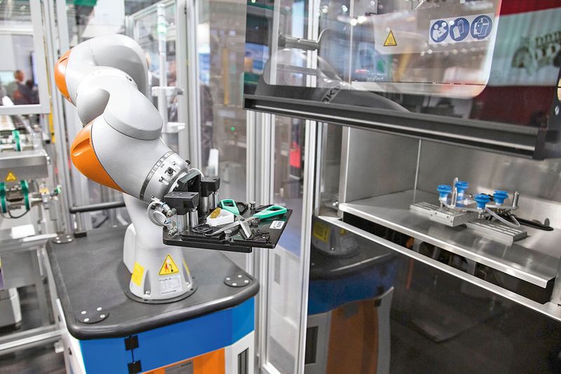 Der Roboter entfernt mit einer auf der Scherenaufnahme angebrachten Bürste Reste anhaftenden Materials. Herausforderung in diesem Prozessteil ist, dass die Temperatur im Bauraum nicht abnehmen darf. (© ARBURG / photovision-dh)