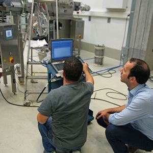 Ein Vertreter von Zeppelin (sitzend) und ein Softwareentwickler überprüfen die an der Anlage angebrachten Sensoren.(Bild:  Oliver Thiel/Zeppelin)