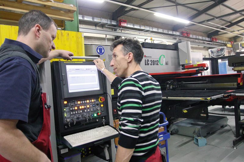 Geschäftsführer Marcel Wüst (links) im Gespräch mit einem Mitarbeiter an der Maschinensteuerung der Amada LC-2012 C1. (Bild: Anne Richter, SMM)