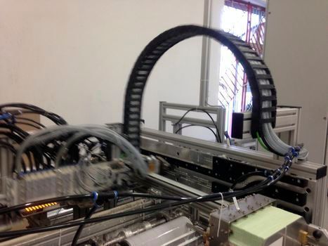 Bild 9: Diese Etikettiermaschine holt sich Etiketten aus dem Vorrat, trägt den Kleber auf und bringt die Etiketten auf der Verpackung an. Da sich der Hauptteil der Maschine nicht nur vor und zurück bewegt, sondern sich auch dreht, gab es Schwierigkeiten, die Versorgungsleitungen für Luft, Strom und Kleber so zu montieren, dass sie nicht gequetscht werden. Die e-kette der Serie 1500 war für dieses Problem die beste Lösung. Die Leitungen werden nun sauber und ohne Quetschungen geführt. (Bild: DINOPOL)